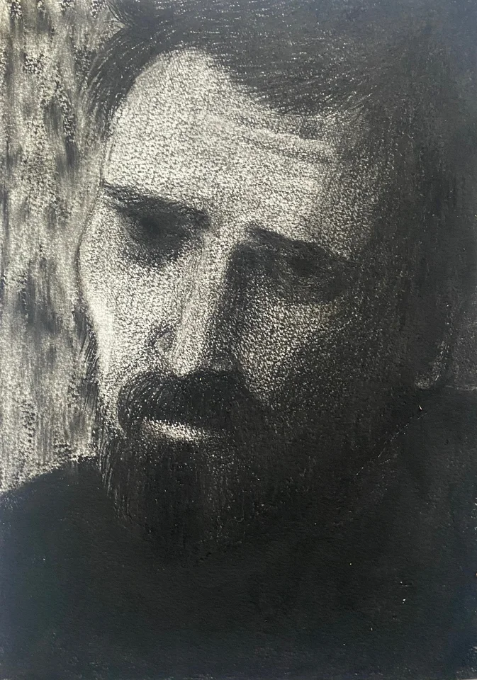 A softly shaded monochrome portrait of a bearded man
